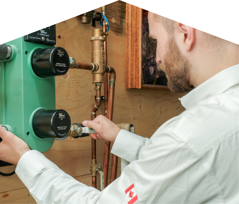 Furnace Guys HVAC specialist performing boiler installation, securing a valve on a new hydronic heating system with copper piping and a green circulation pump mounted on a wooden wall. Furnace Guys HVAC specialist performing boiler installation, securing a valve on a new hydronic heating system with copper piping and a green circulation pump mounted on a wooden wall.