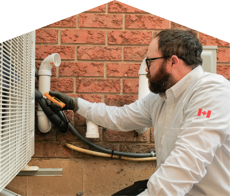 Furnace Guys HVAC specialist checking insulated piping on a heat pump unit beside a brick wall during a diagnostic service. Furnace Guys HVAC specialist checking insulated piping on a heat pump unit beside a brick wall during a diagnostic service.