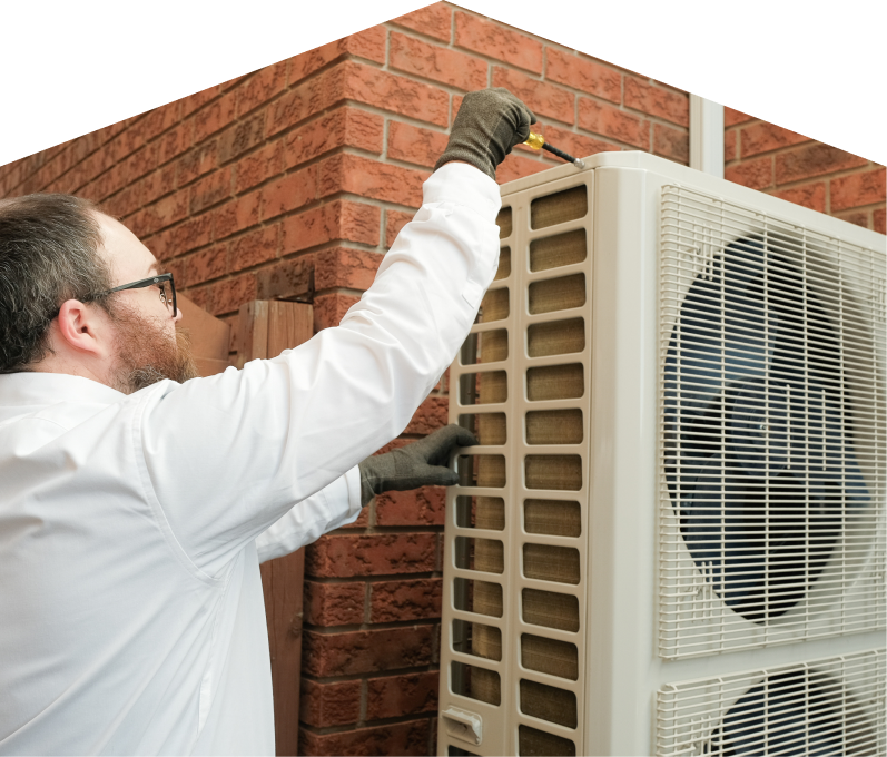 Furnace Guys HVAC specialist using a screwdriver to complete a heat pump installation beside a brick wall. Furnace Guys HVAC specialist using a screwdriver to complete a heat pump installation beside a brick wall.