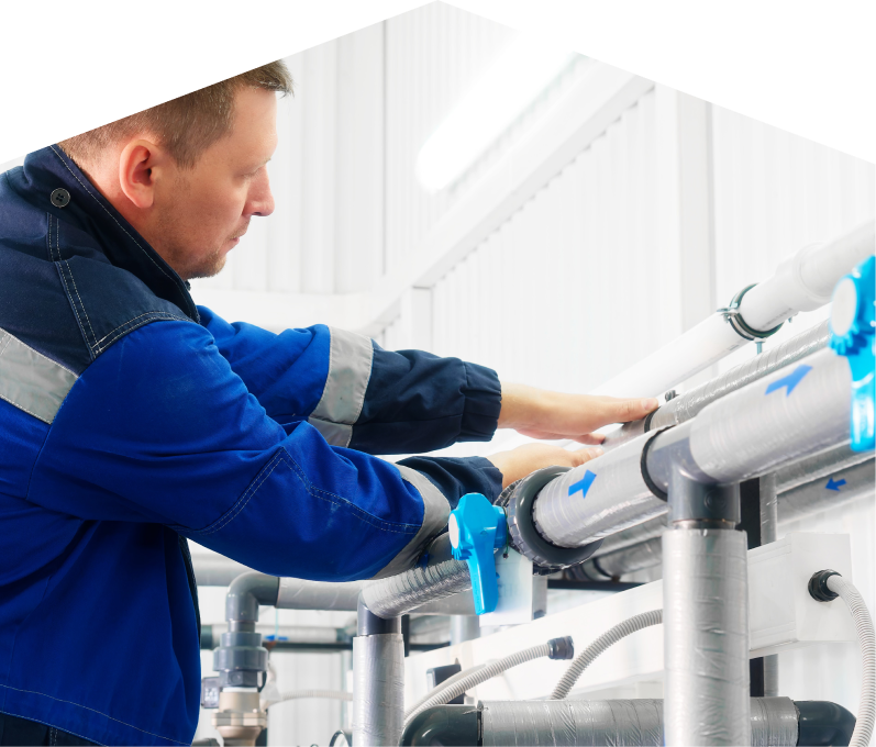 Furnace Guys water damage and restoration specialist in a blue uniform adjusts insulated piping on a water system inside a bright utility room. Furnace Guys water damage and restoration specialist in a blue uniform adjusts insulated piping on a water system inside a bright utility room.